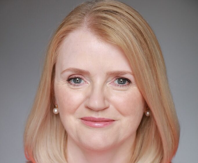 Headshot of Catherine McCarthy wearing a red dress and pearl earrings.