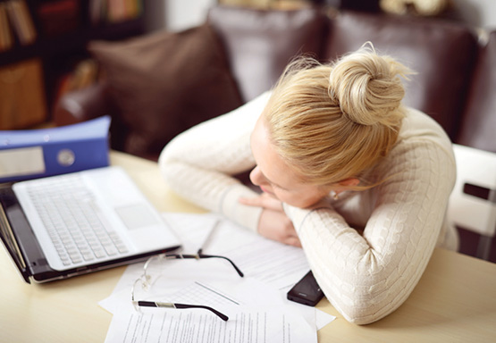 Woman holding her head in her hands at a desk