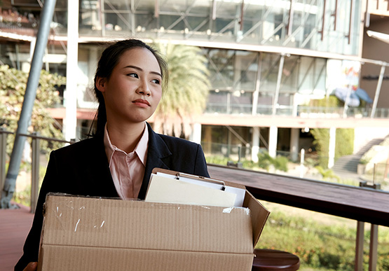 Woman leaving workplace with her belongings in a cardboard box