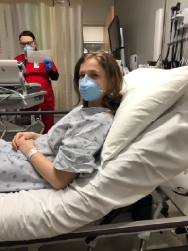 Woman in a hospital bed wearing a mask