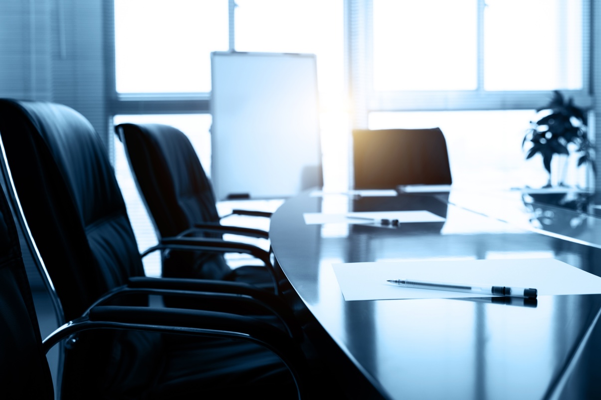 Close up of boardroom table and chairs in semi-darkness