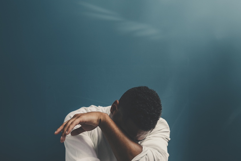 Man with head in hands against deep blue backdrop