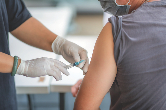 Clinician administering Covid vaccine into patient's arm