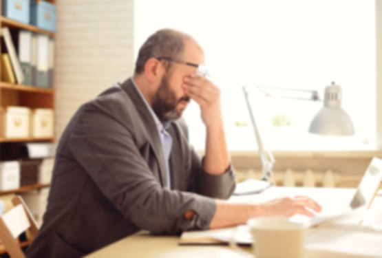 Man with his head in his hands at a desk