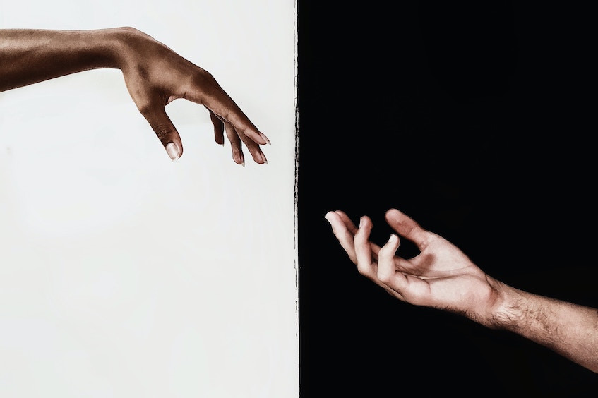 Black hand and white hand reaching out to each other