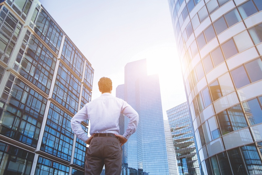 Man in street looking up at office buildings