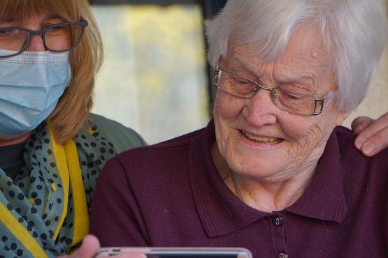 Care worker & elderly client looking at phone